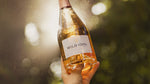 A bottle of WILD IDOL Alcohol Free Sparkling Rosé Wine being held to the sky.