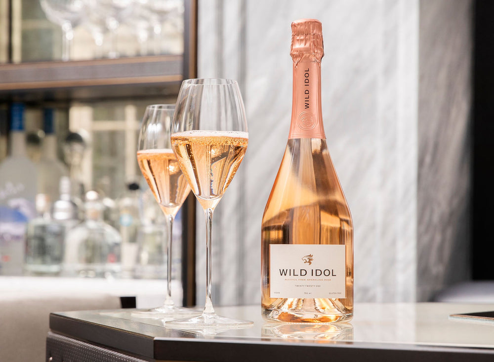 Two glasses of rosé and a bottle on a marble counter, showcasing the best non alcoholic wine UK offerings.