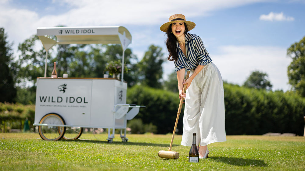 Lady enjoy a game of croquet to a backdrop of a mobile bar selling WILD IDOL Alcohol Free Sparkling Wine