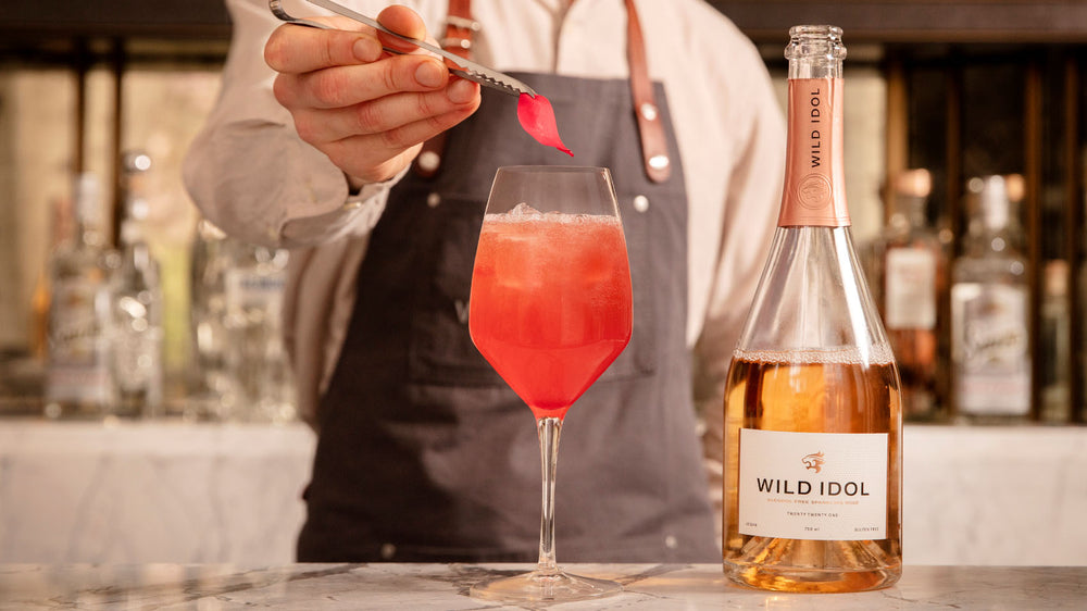 Mixologist adding a flower petal to a cocktail using Wild Idol non alcoholic sparkling rose