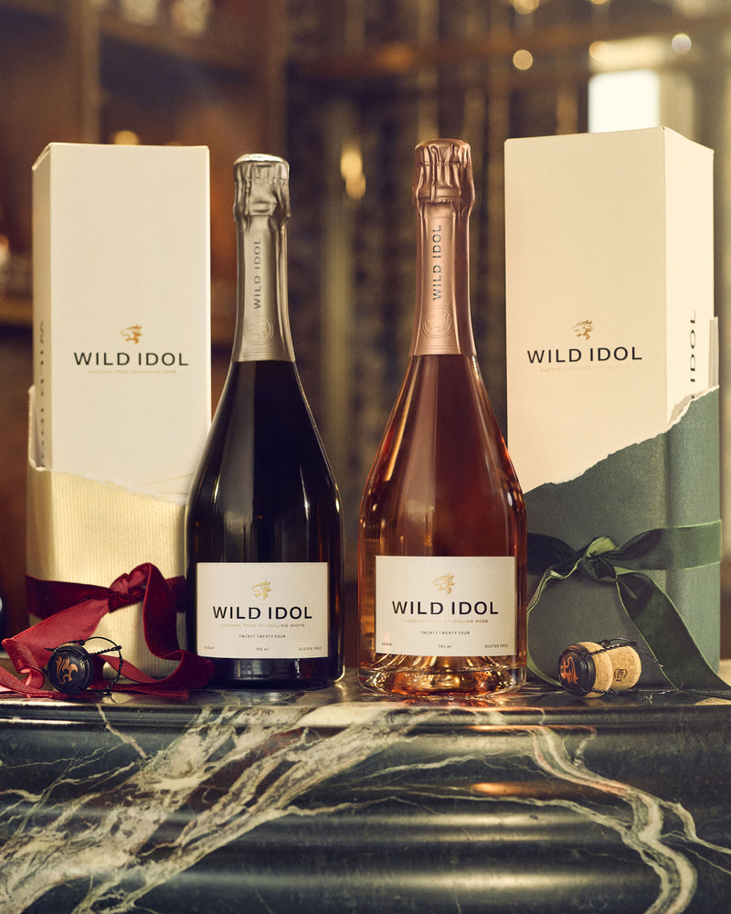 Two bottles of WILD IDOL Alcohol Free Sparkling White & Rosé Wine standing next to their boxes.