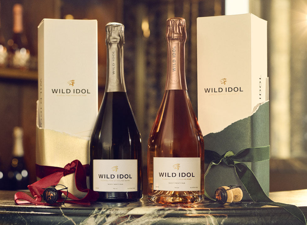 Two bottles of WILD IDOL Alcohol Free Sparkling White & Rosé Wine standing next to their boxes.